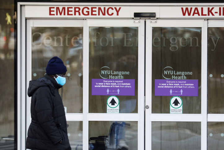 Pedestrian in mask walks by emergency room doors