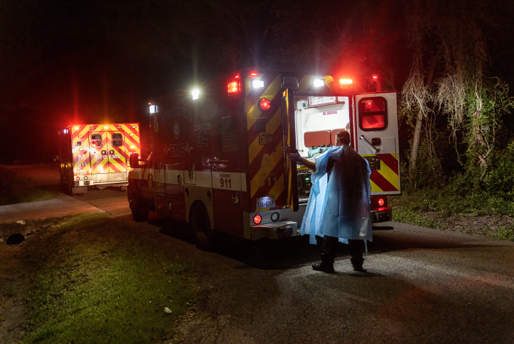 Ambulance on the road at night with EMT pulling patient out on stretcher