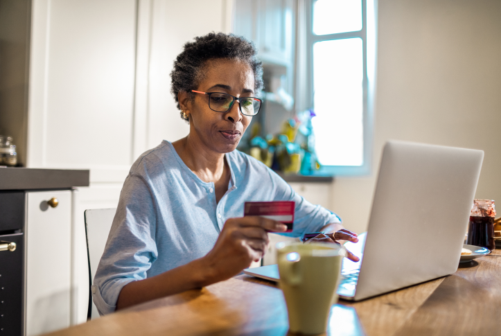 woman looks at credit card while typing into computer