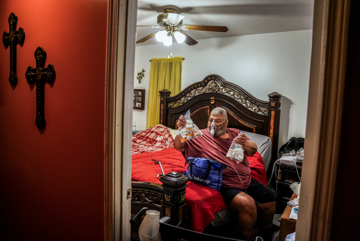 Man sits on bed going thru medications