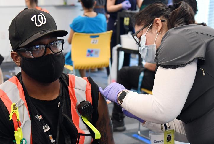 Registered nurse Rocio Ortiz administers a Moderna COVID-19 vaccine to Amazon employee Andre DuPree