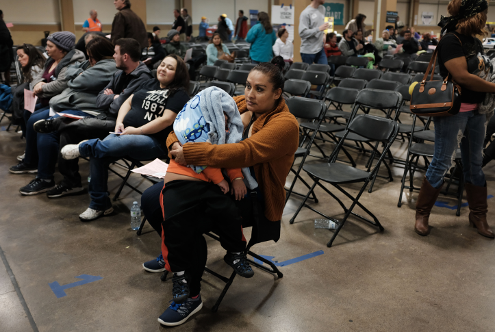 Mom and child sit in waiting room with tons of chairs of health clinic