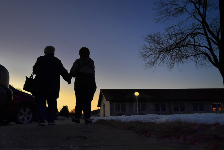 Photo, silhouette of two elderly adults holding hands in front of the setting sun