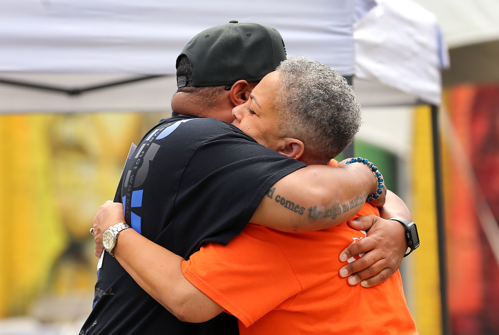 Black man and woman embrace in an outdoor fair welcoming formerly incarcerated community members