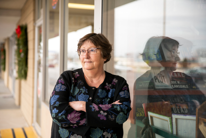 Photo, woman standing outside of bookshop with arms crossed