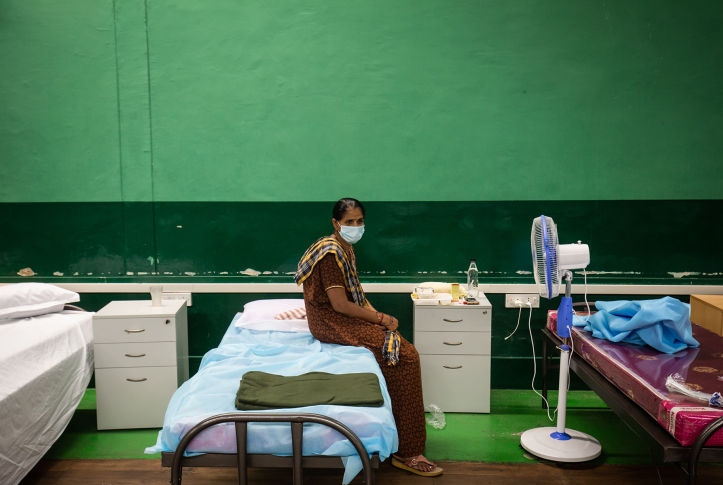 Indian patient sits on hospital bed with mask in Indian hospital room