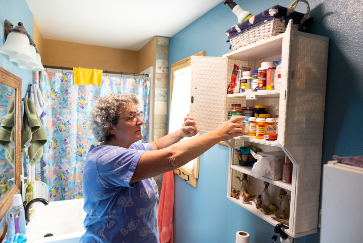 Photo, woman reaching into medicine cabinet