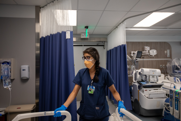 Doctor in mask holds corners of hospital bed