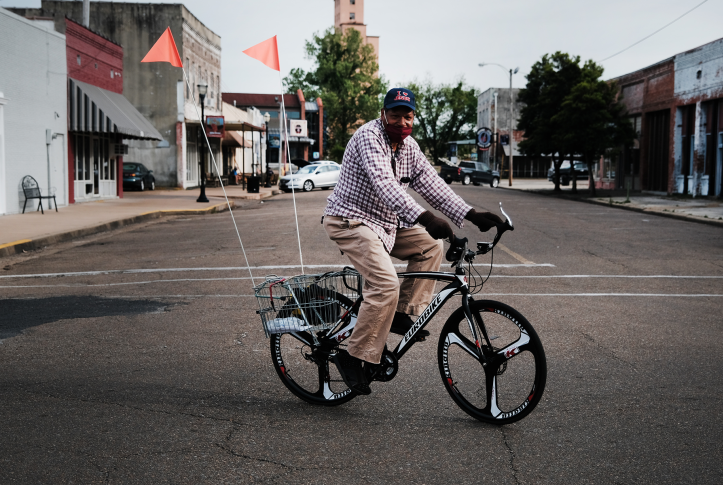 Man in mask rides in neighborhood on bike