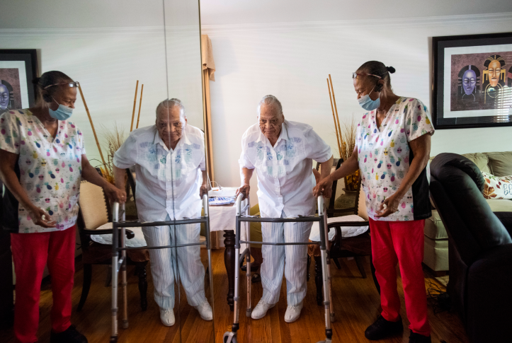 Elderly woman with walker is helped by a in-home nurse.