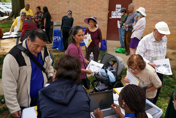 Photo, group of people get paperwork from workers at laptops