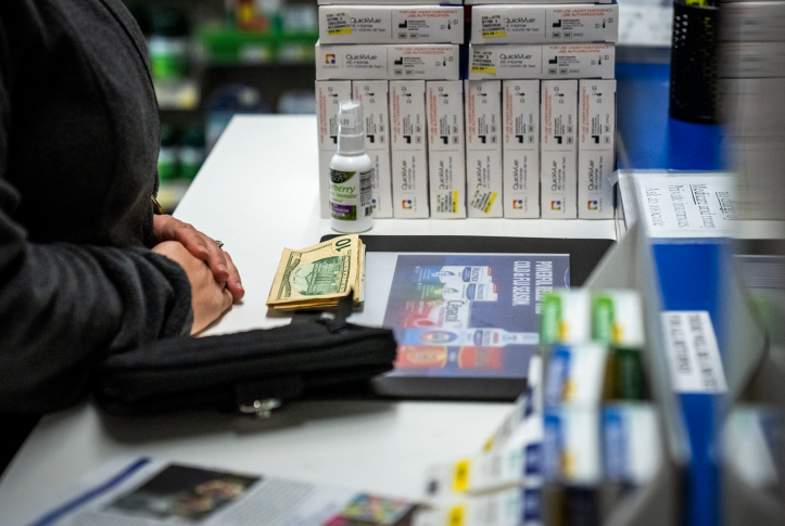 Photo, hands paying in cash for prescription at a pharmacy counter
