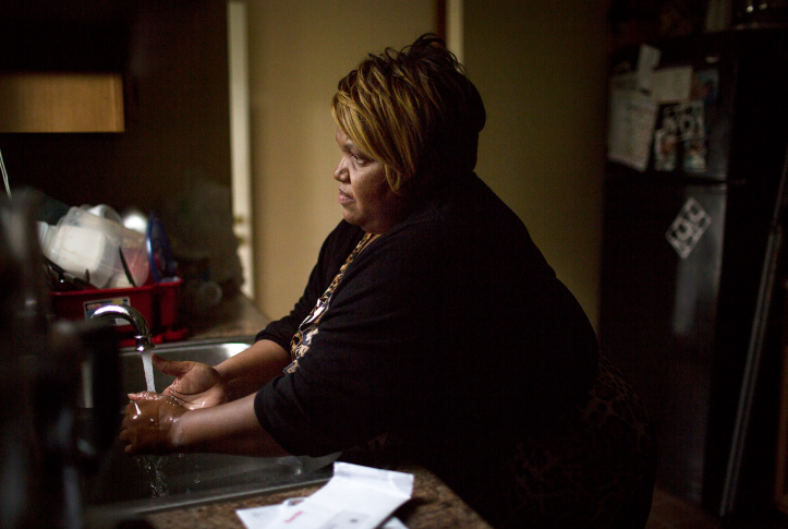 Photo, woman washes hands at kitchen sink