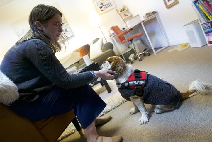 woman pets her dog seated in front of her