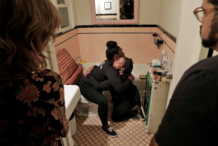 Doulas demonstrating how a birthing person can be supported while in hte bathroom