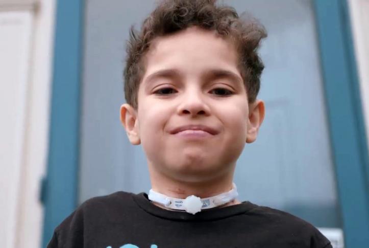 Ten-year-old Isaac smiling in front of his house