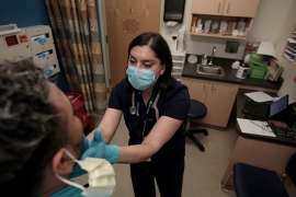 Photo, Doctor examines patients throat with her gloved hands.