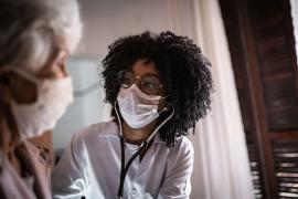 Doctor wearing a surgical mask speaks to a patient