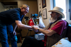 Photo, man shakes hand of other seated elderly man