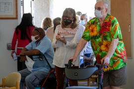 Elderly man and daughter wait in line with walker