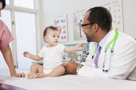 Baby on doctors table reaches for doctor
