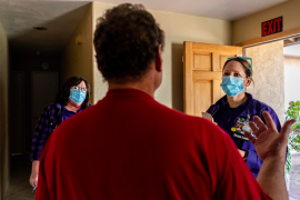 Photo, back of man talking to two masked women