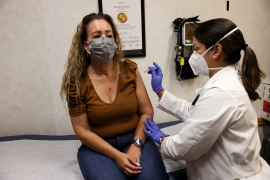 Masked woman receives a vaccine from a medical professional