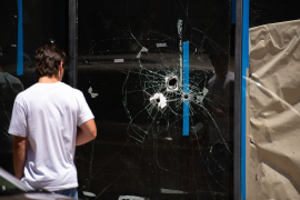 Photo, Man looks at bullethole in store window