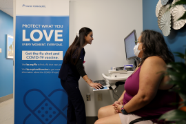 Woman prepares to get covid vaccine, while talking to nurse on computer.
