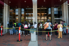 People wait in line in front of building