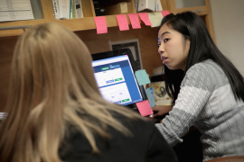 Woman helps woman on laptop