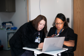 two clinic workers look at laptop