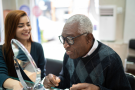 elderly gentleman tries on glasses and looks in the mirror
