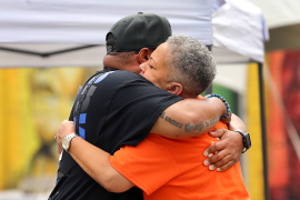 Black man and woman embrace in an outdoor fair welcoming formerly incarcerated community members