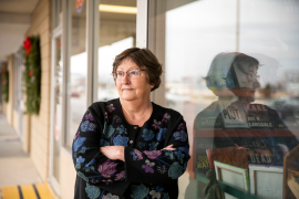 Photo, woman standing outside of bookshop with arms crossed