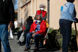 senior man sits in chair waiting in line for vaccine