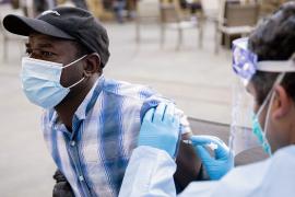 Black American wearing a surgical mask recieves a vaccine dose