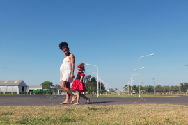 pregnant mom and daughter walk barefoot in front of rural homes