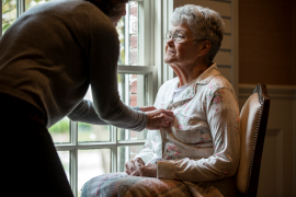 daughter helps elderly mother button shirt