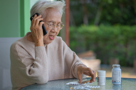 senior woman on phone looks at pill packets on table